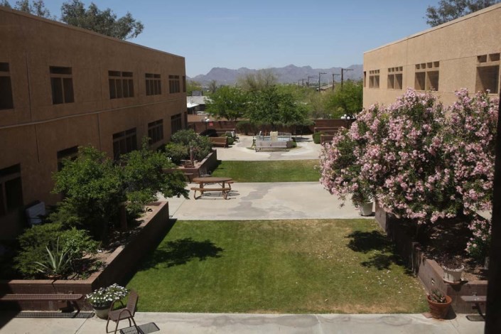 A sunny courtyard surrounded by buildings with a view of distant mountains.