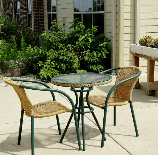 A cozy outdoor seating area featuring a glass table and two wicker chairs, perfect for enjoying a sunny day.