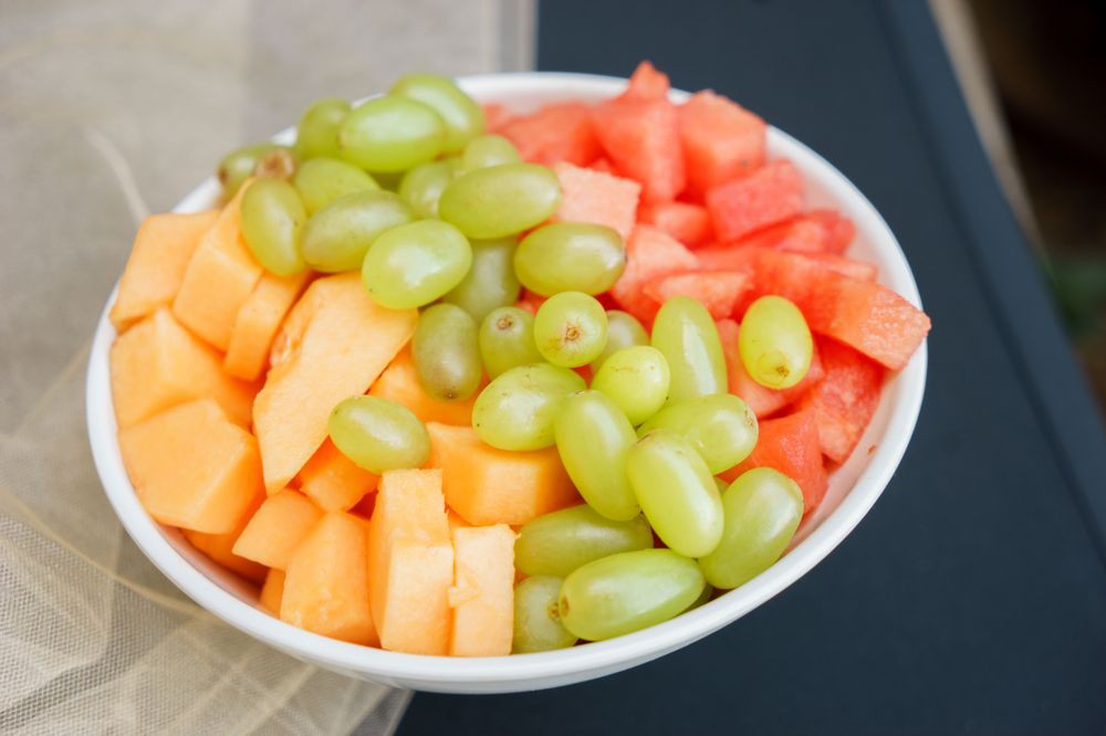 A bowl of fresh fruit featuring grapes, melon, and watermelon.
