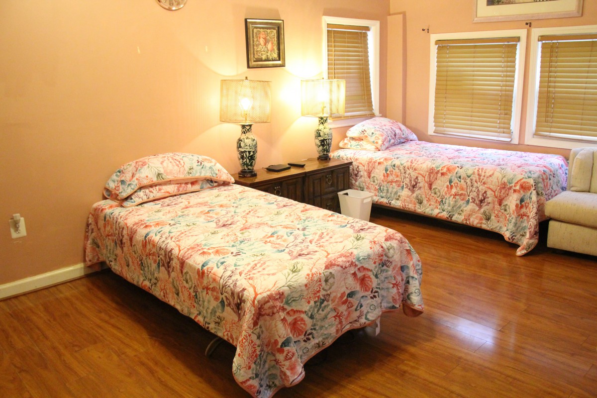 A cozy bedroom featuring twin beds with floral bedding and warm lighting.