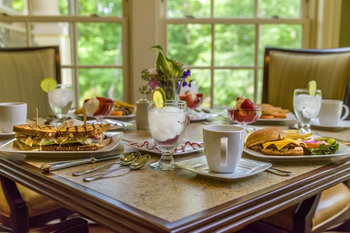 A beautifully set breakfast table with a variety of dishes and drinks, overlooking a scenic window view.