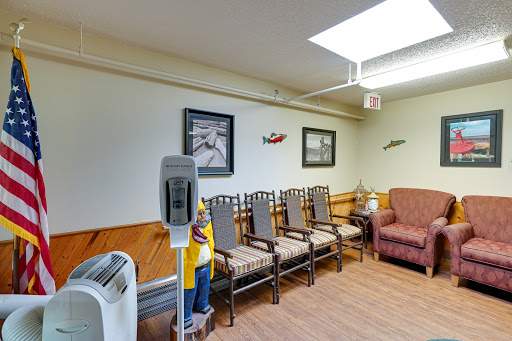 A waiting area in a hospital featuring several chairs, a couch, and artwork on the walls.