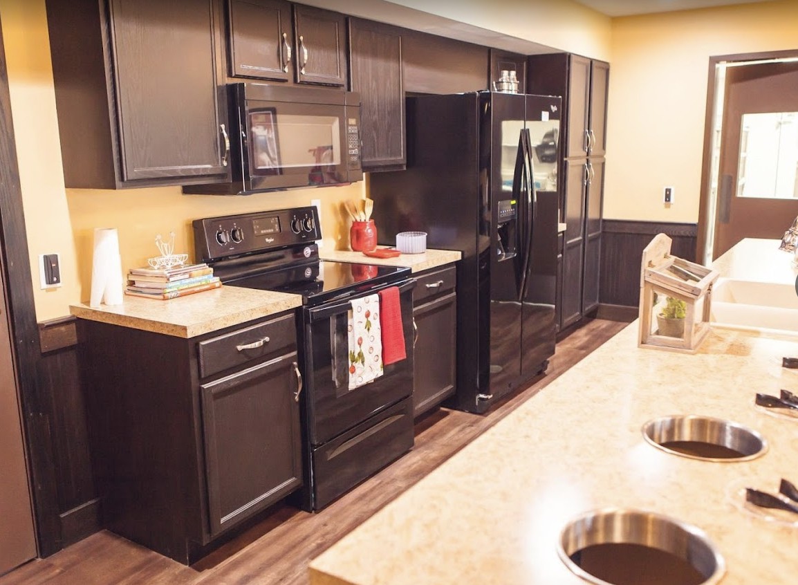 A modern kitchen featuring dark cabinets, countertops, and various appliances.