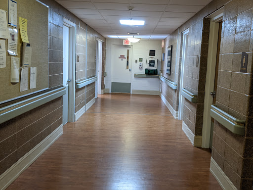 A quiet corridor in a hospital, featuring a well-lit environment and wooden flooring.