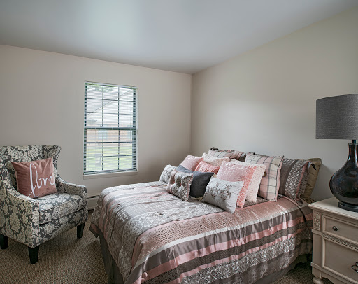 A cozy and stylish bedroom featuring a comfortable bed adorned with various pillows and a charming armchair.