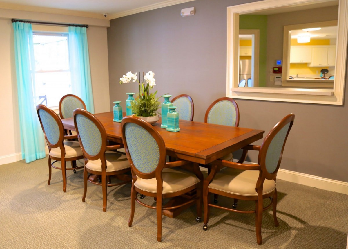 A modern dining room with a large wooden table surrounded by upholstered chairs and decorative vases.