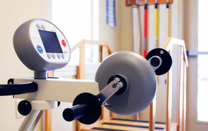 Exercise equipment in a physical therapy setting, featuring a machine with adjustable settings.