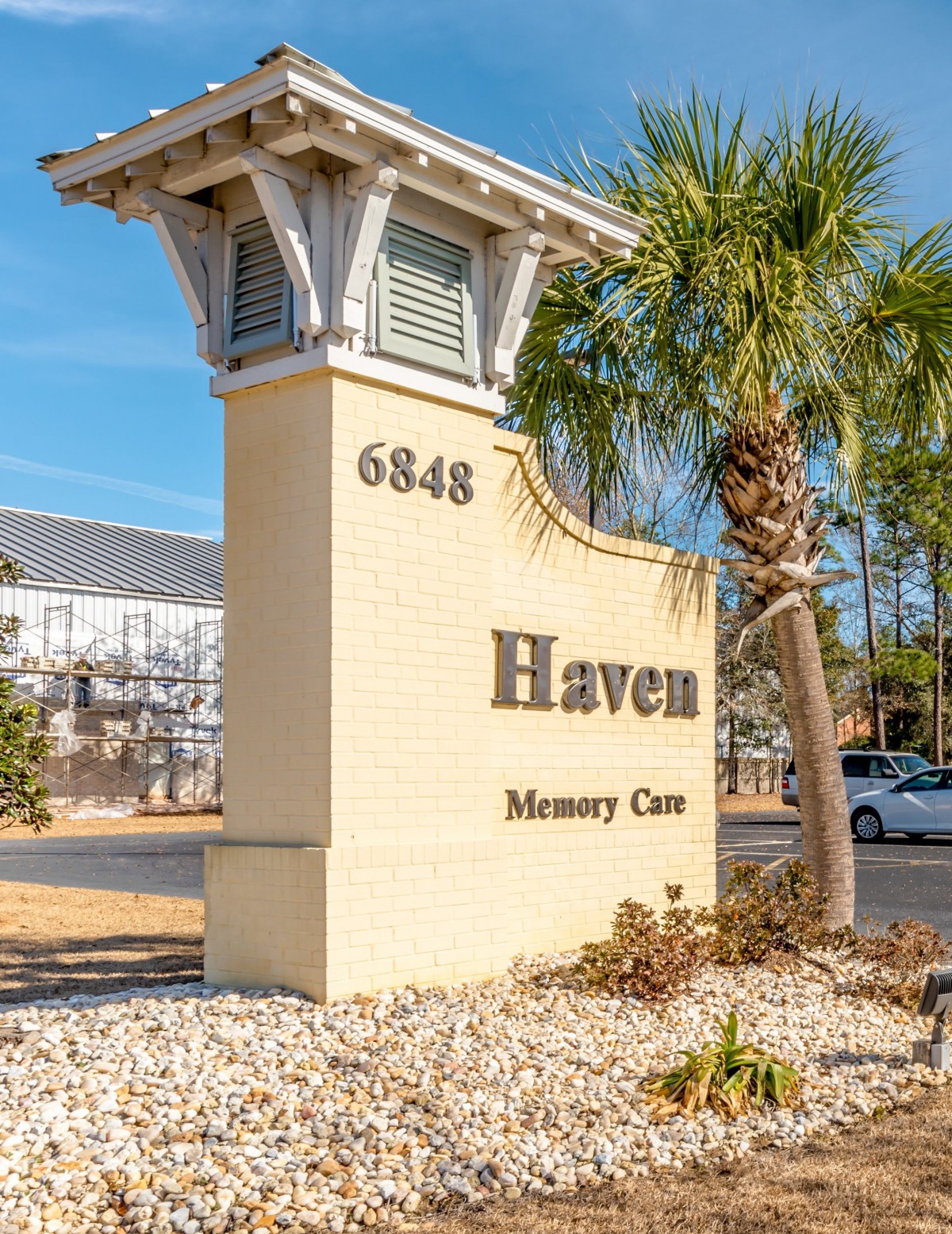 A sign for 'Haven Memory Care' with an address, located next to a palm tree.