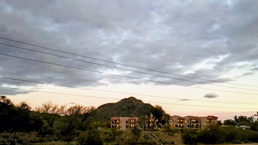 A serene view of a mountain under a cloudy sky, with buildings in the foreground.