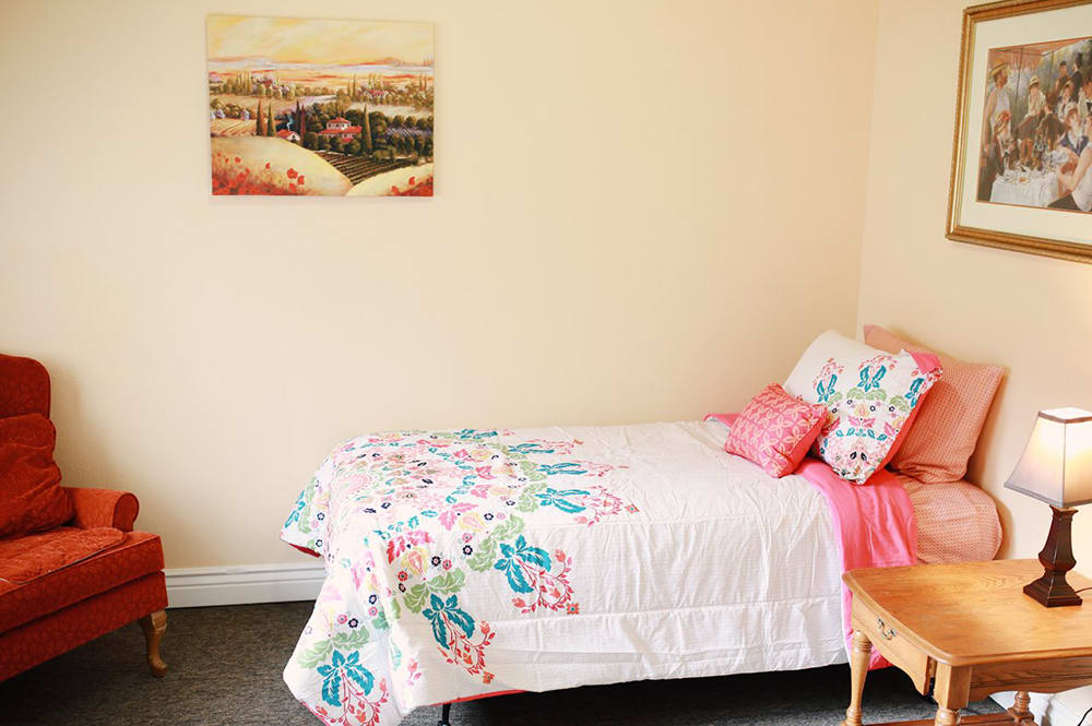 A cozy bedroom featuring a single bed with colorful bedding and wall art.