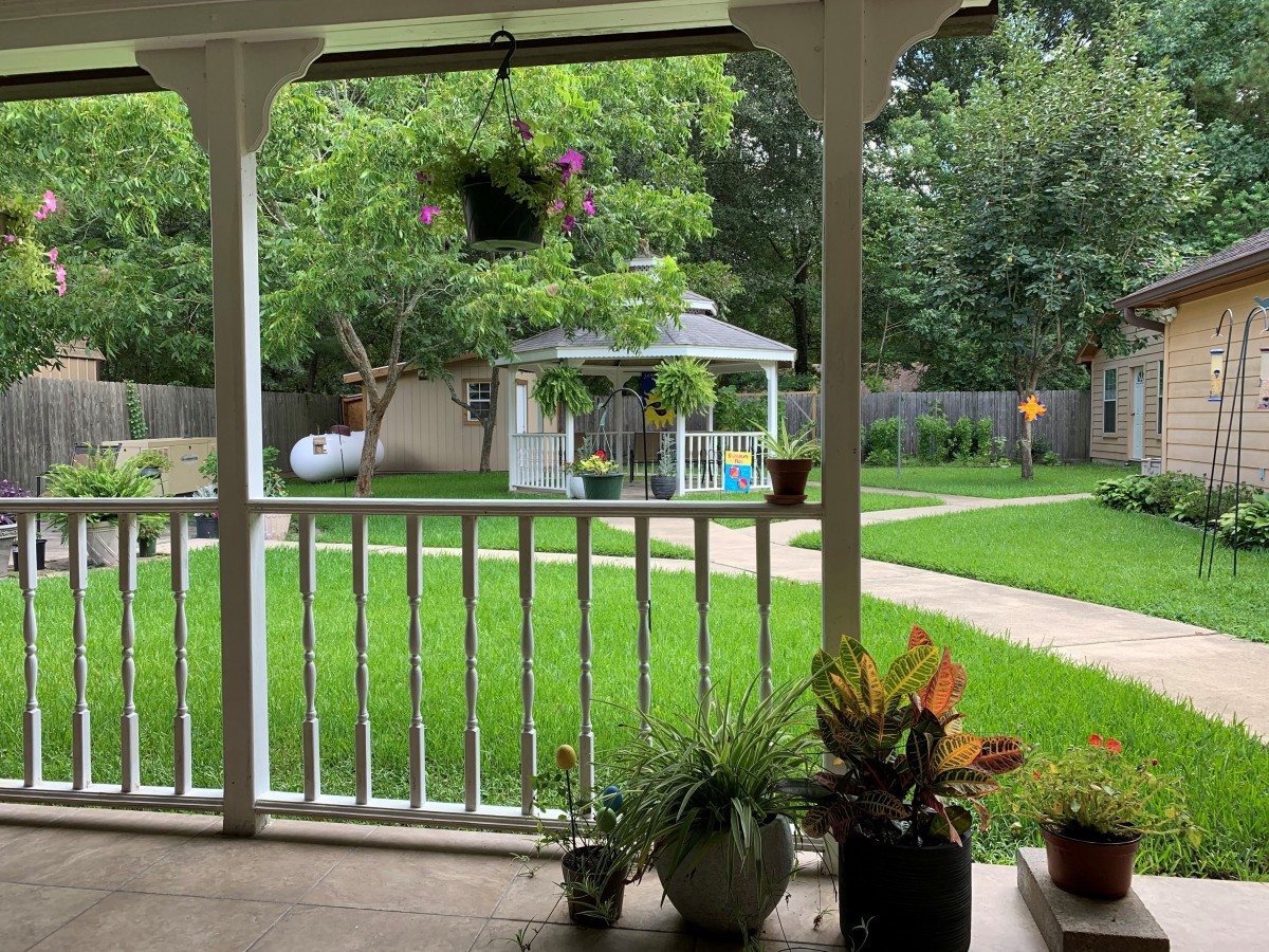 A serene view from the porch overlooking a lush garden with a gazebo.