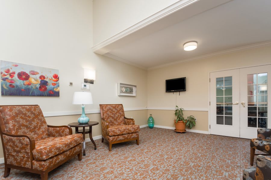 A cozy living room with comfortable chairs, a TV on the wall, and decorative elements.