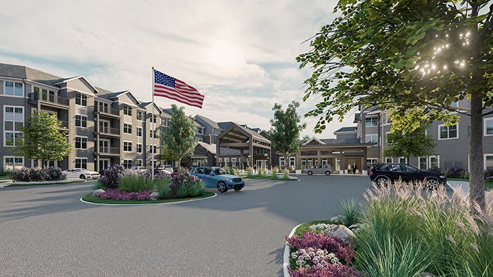A residential complex with landscaped surroundings, featuring apartment buildings and an American flag.
