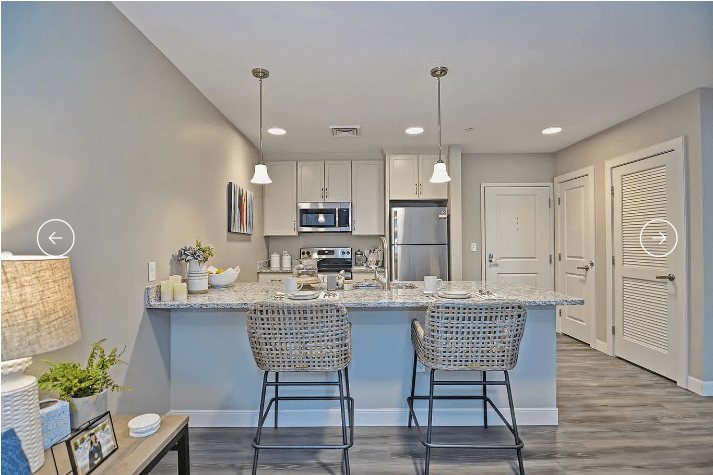 Modern kitchen with bar seating, pendant lighting, and stainless steel appliances.