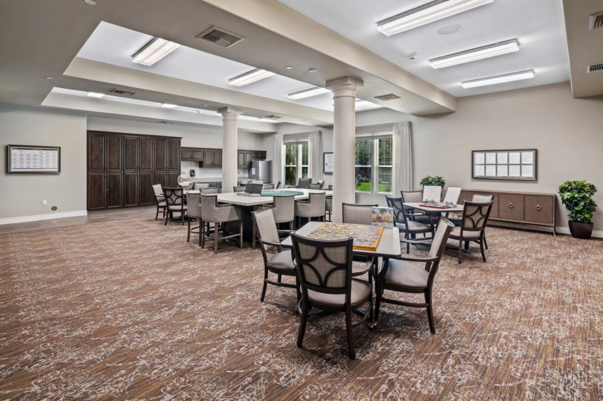 A spacious and well-lit dining area with several tables and chairs, featuring skylights and large windows.