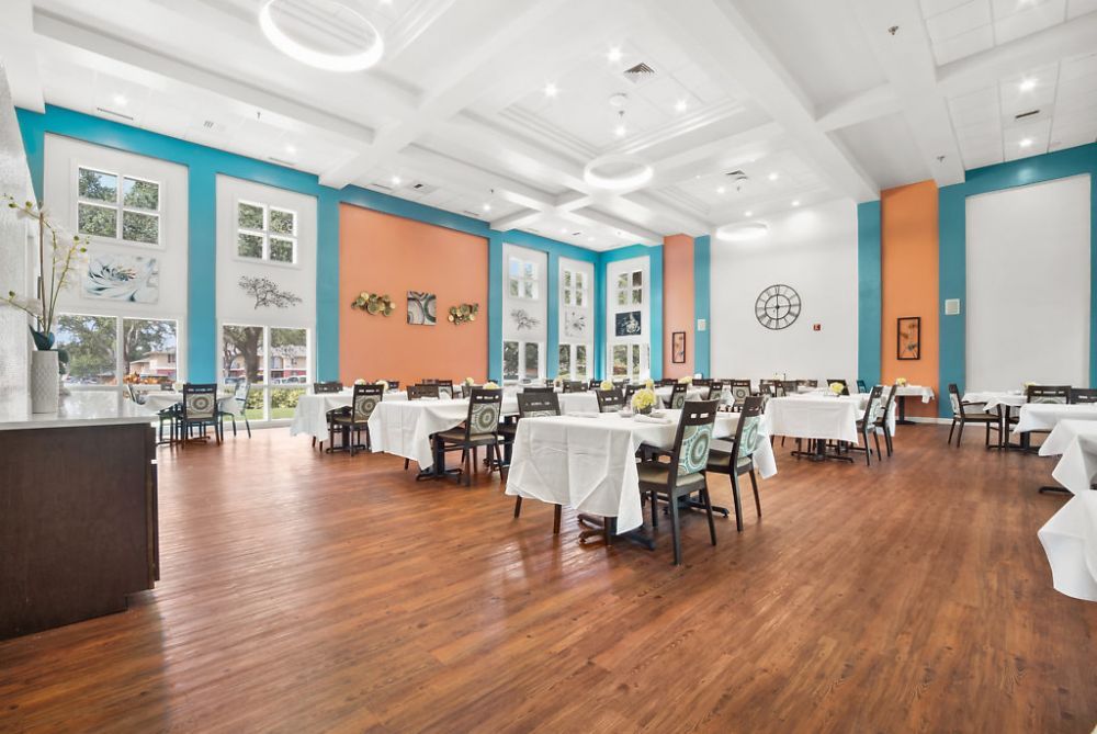 A spacious and modern dining area with neatly arranged tables and chairs, featuring colorful walls and a wooden floor.
