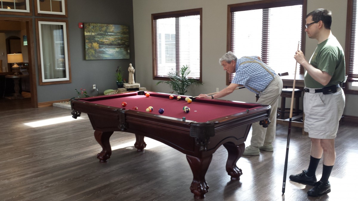 A person playing billiards on a red pool table in a game room.