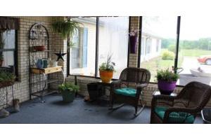 A cozy sunroom with rocking chairs and various potted plants by a large window.