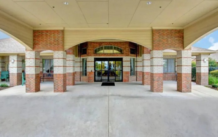 A brick building entrance with a glass door and overhang.