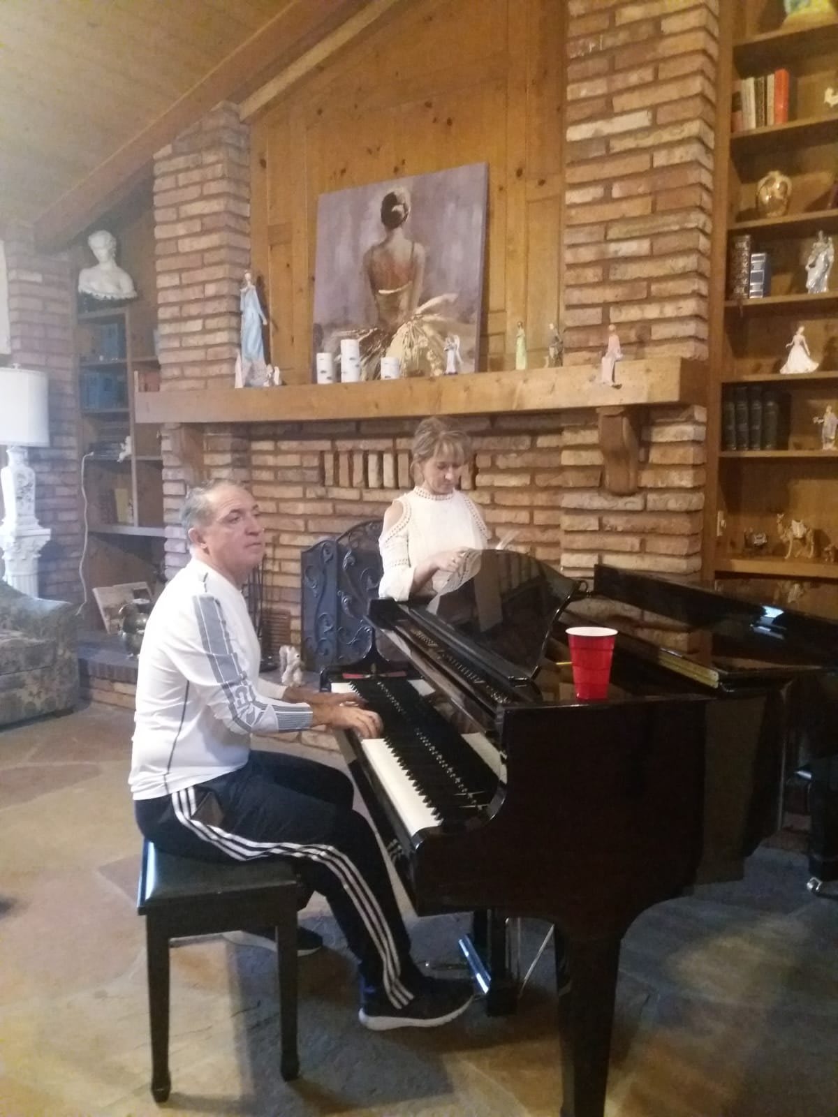 A person playing the piano in a cozy living room with brick walls and various decorations.
