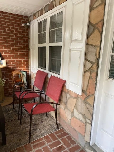 A cozy porch area with red chairs against a brick and stone wall.