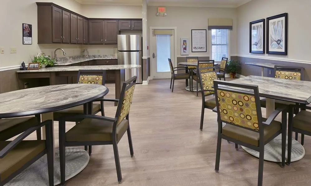 A modern kitchen and dining area with tables and chairs, featuring a stainless steel refrigerator.