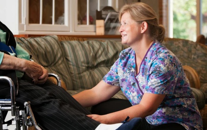A caregiver smiling while attending to a patient at home.