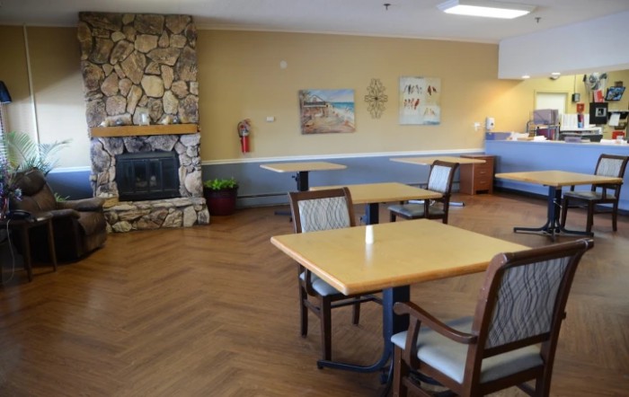 A cozy dining area with tables and chairs, featuring a stone fireplace and wall art.