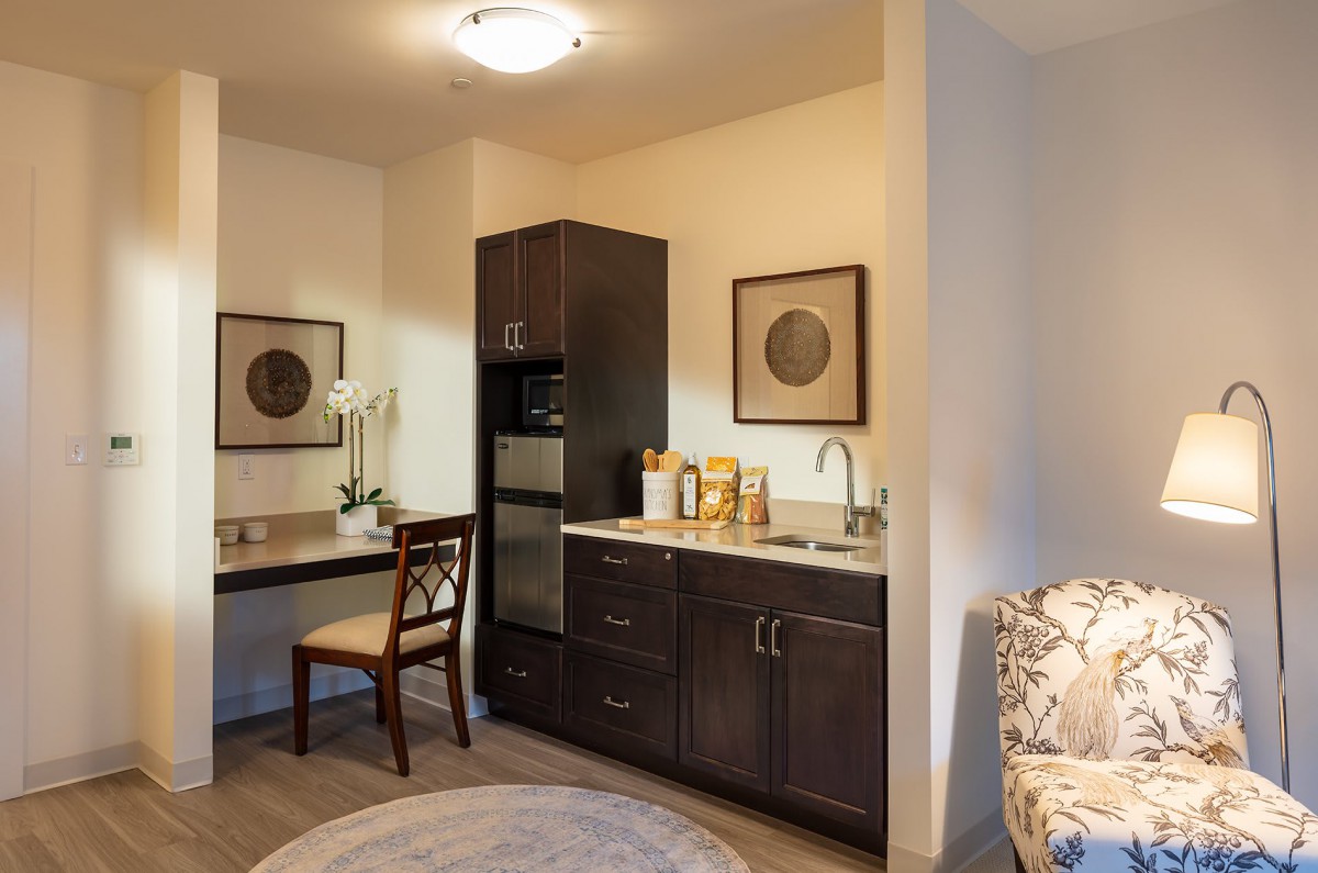A modern kitchenette area with dark cabinets and a cozy seating arrangement.