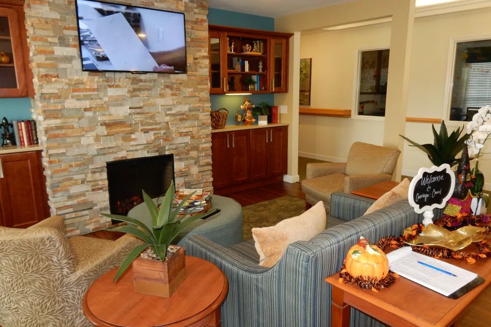 A cozy living room with a stone fireplace, comfortable seating, and a television mounted on the wall.