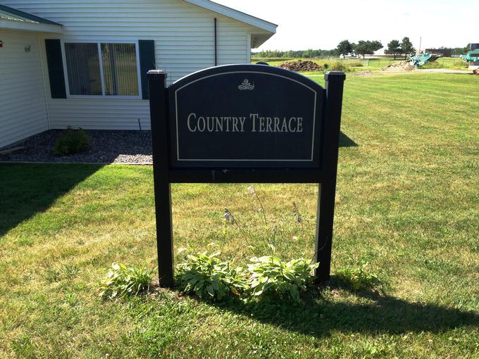 Sign for Country Terrace in front of a building and lawn.