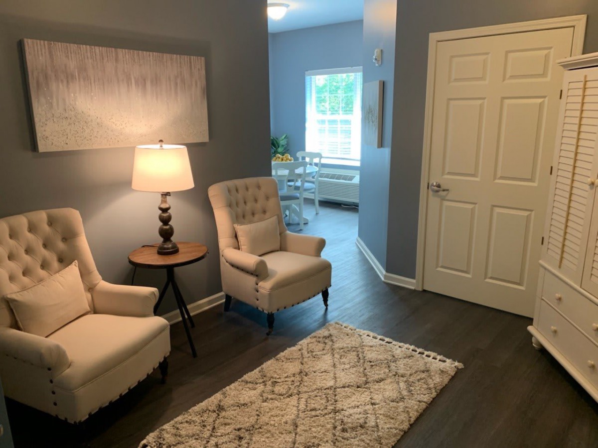 A cozy living room with two armchairs, a lamp, and a decorative rug set against blue walls.