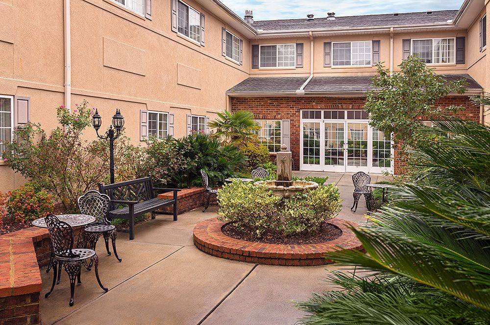 A charming courtyard with a central fountain, surrounded by benches and lush greenery.