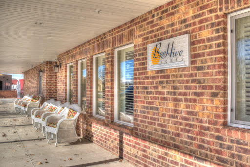 A cozy brick building entrance featuring a welcoming sign and outdoor seating.