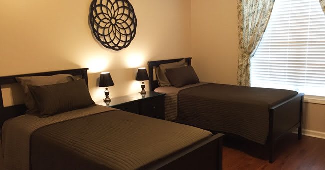 A cozy bedroom with twin beds, featuring warm lighting and elegant wall decor.