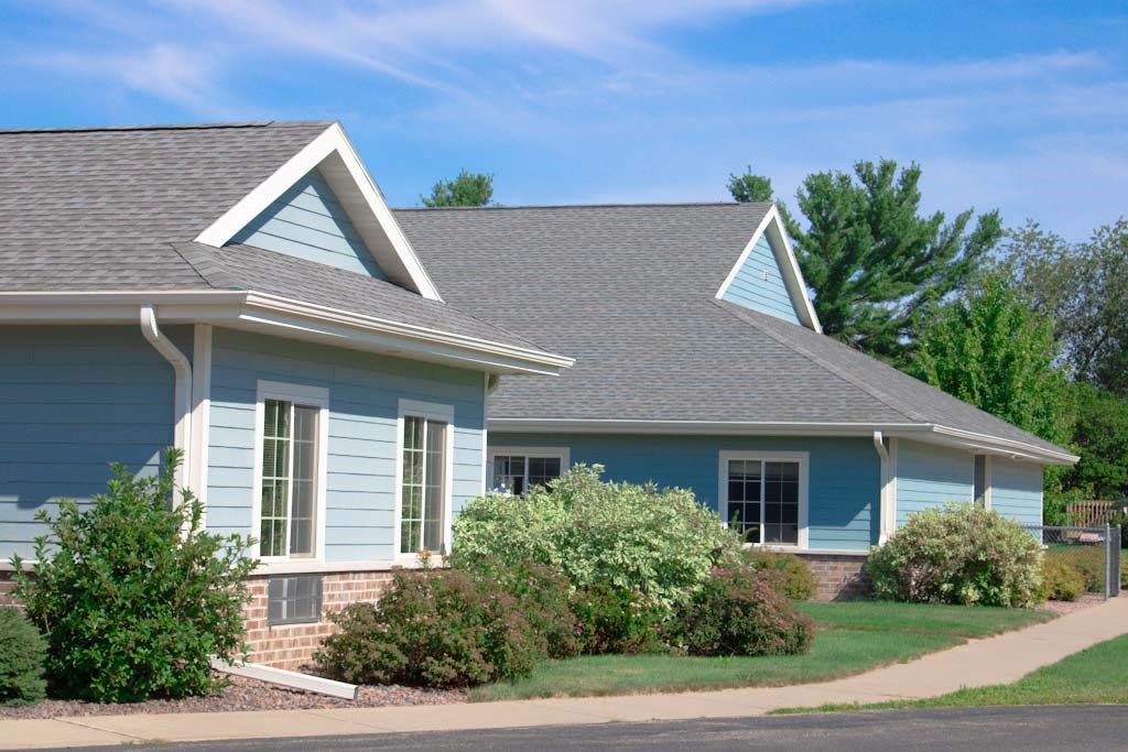 A charming suburban house with well-maintained landscaping and a clear blue sky.