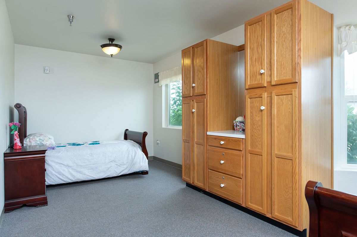 A minimalist bedroom with a bed and wooden wardrobe.