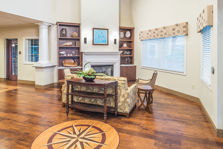 A cozy living room with a fireplace, wooden floors, and decorative shelving.