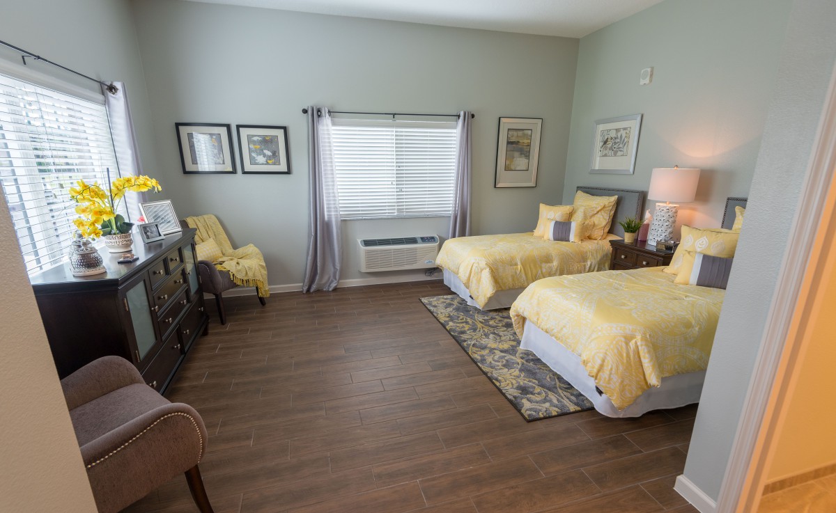 A well-decorated bedroom with twin beds featuring yellow bedding and hardwood floors.