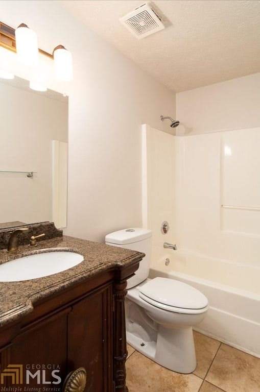 A modern bathroom with a vanity, toilet, and shower-bathtub combination.