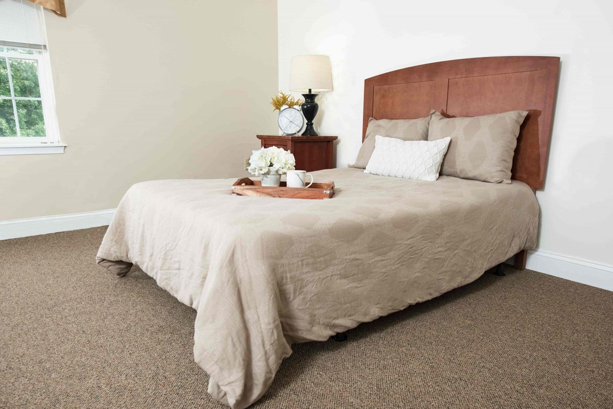A neatly made bed in a cozy bedroom, featuring elegant decor with flowers on a tray.