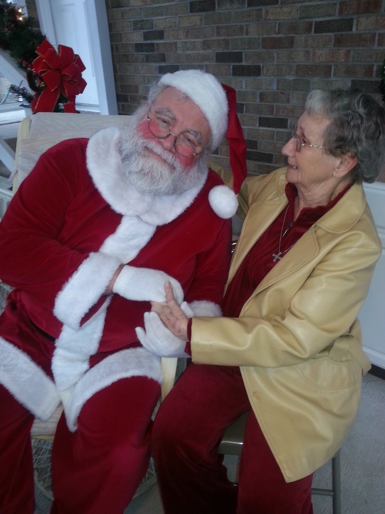 An elderly woman joyfully interacting with Santa Claus, capturing the festive holiday spirit.