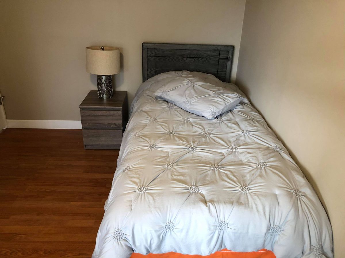 A cozy bedroom with a single bed, nightstand, and lamp.