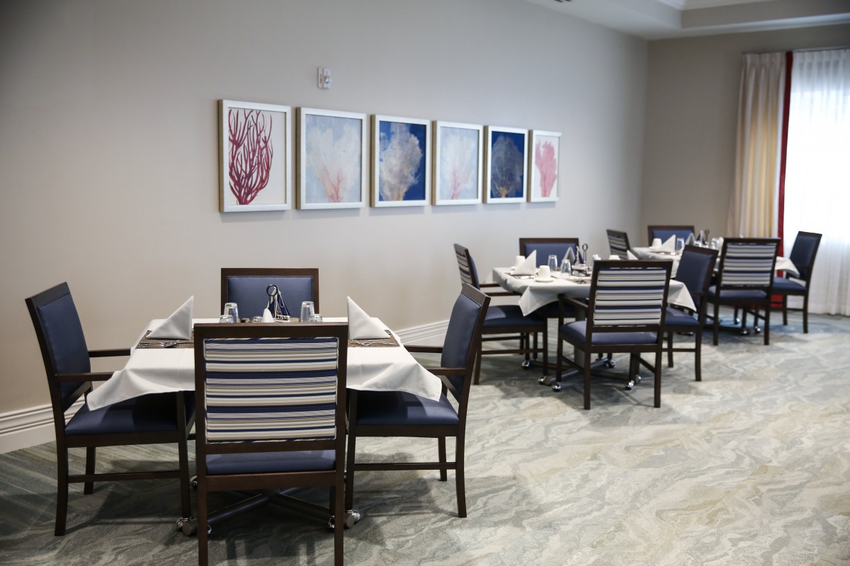 A cozy restaurant dining area with neatly arranged tables and chairs, adorned with artwork on the walls.