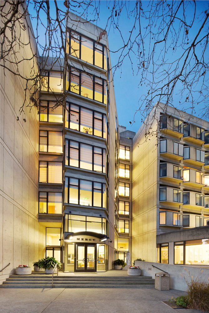 A modern, illuminated building stands out against the evening sky.