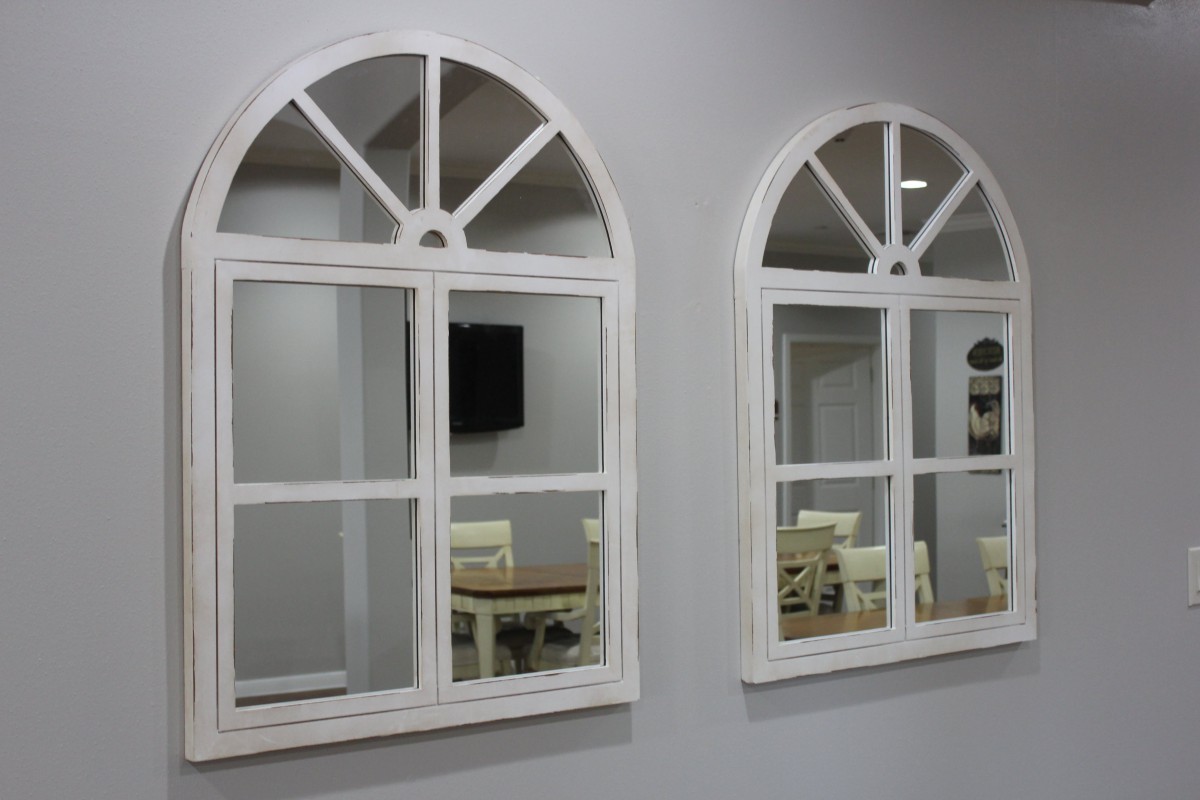 Two arched mirrors reflecting a room's interior design.
