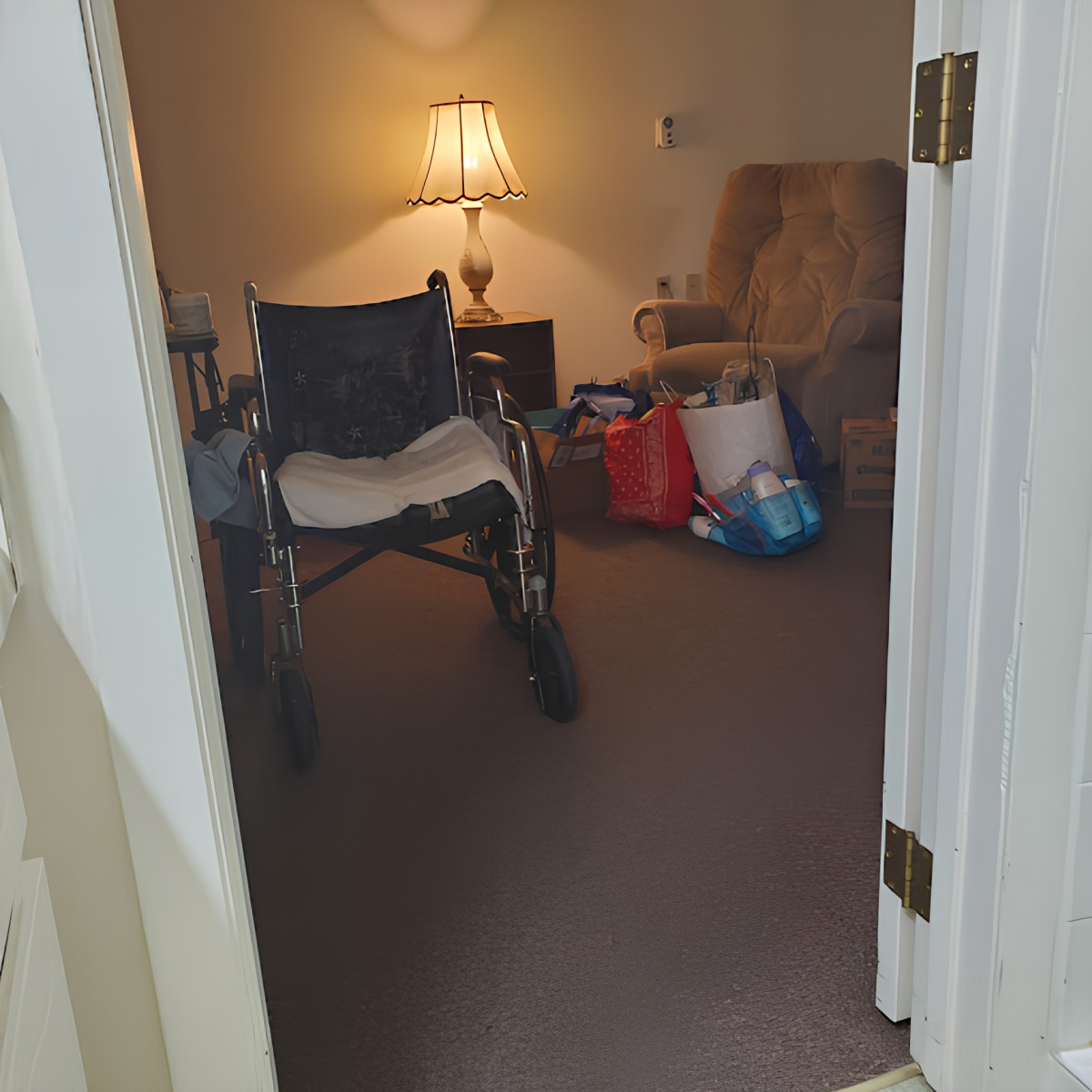 A cozy living room with a wheelchair, lamp, and other furniture visible.