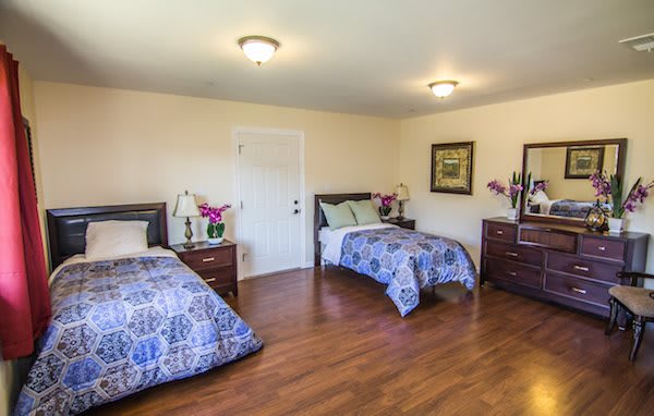 A cozy bedroom with two single beds, featuring wooden floors and decorative elements.