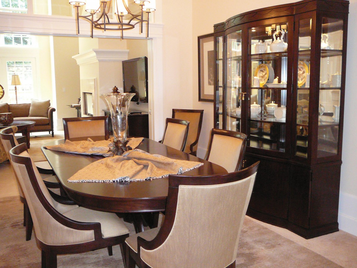 A well-decorated dining room featuring a wooden dining table with matching chairs, an elegant chandelier overhead, and a china cabinet displaying fine dishware.