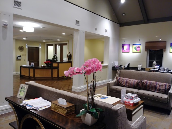 A spacious and well-lit waiting room with a reception desk, sofa, and decorative flowers.
